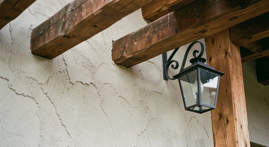 Hand troweled plaster wall meeting heavy timber beams and a wrought iron lantern