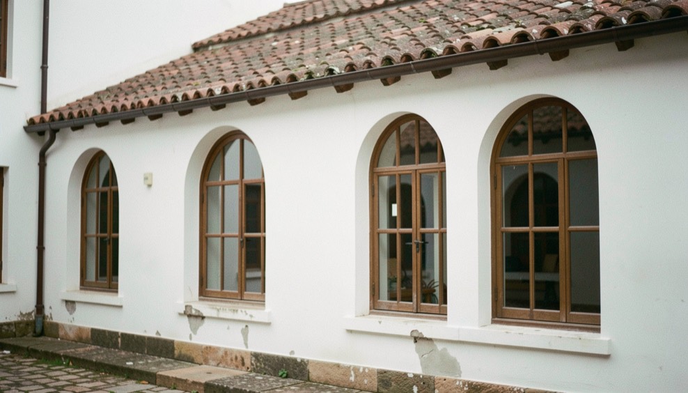 Close view of arched windows, white plaster walls and weathered clay tiles on a courtyard facade